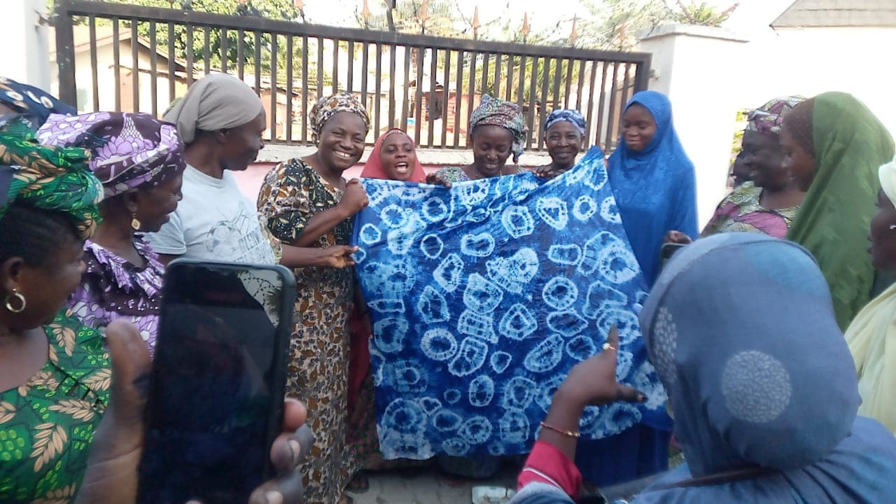 Women showcasing tie-dye fabric from vocational training